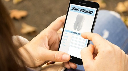 a person holding a phone with dental insurance