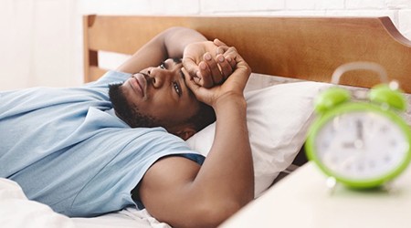 a man looking tired while lying in bed