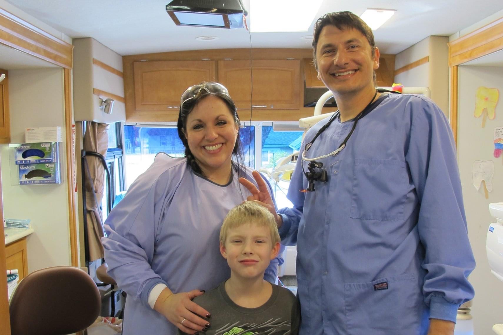 Dental team member and young patient smiling together