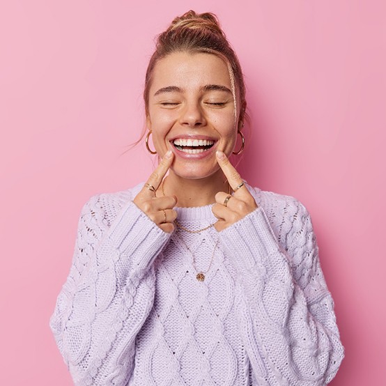 Happy young woman pointing at her teeth