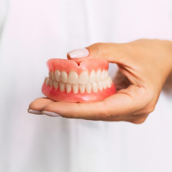 Close up of dentist holding dentures in Eugene