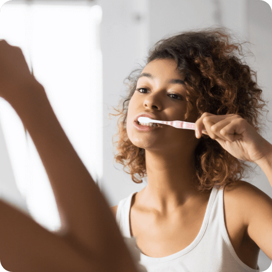 Woman brushing teeth to prevent dental emergencies