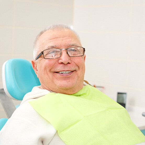 senior man with glasses sitting in dental chai