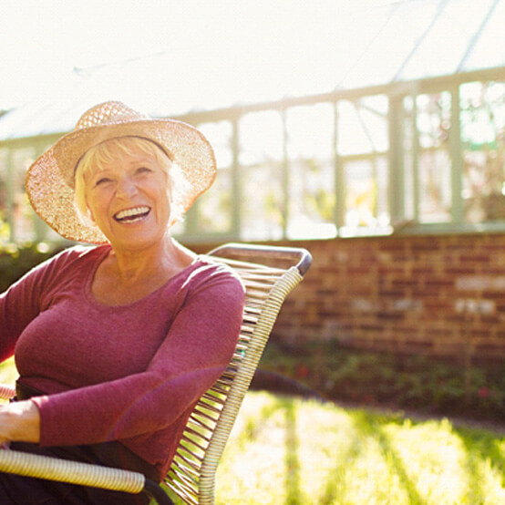 seniro woman with hat sitting and smiling outside