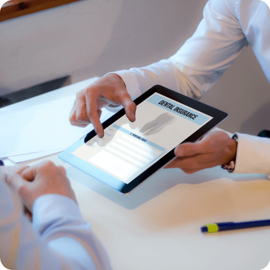 Dentist and dental patient looking at dental insurance forms on tablet computer