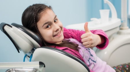 Child giving thumbs up after fluoride treatment