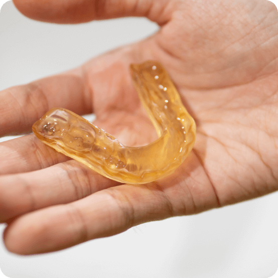 Hand holding a custom nightguard for bruxism