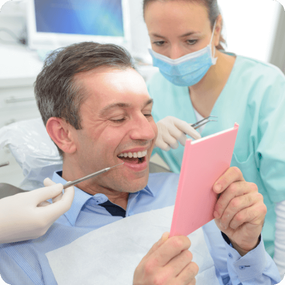 Man looking at smile after replacing missing teeth with dental bridges