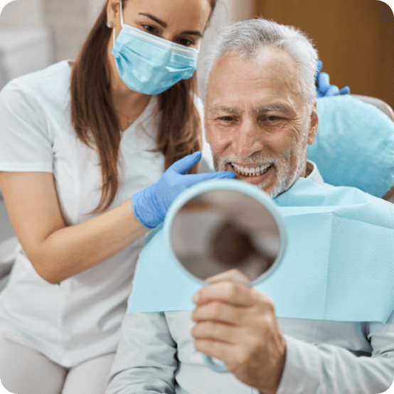 Man looking at smile after tooth replacement with dental implants