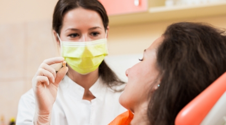 Dentist holding up tooth after non surgical tooth extraction