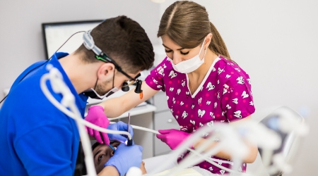 Dentist and dental team member performing root canal treatment procedure