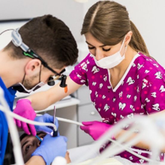 Dentist and dental team member performing root canal treatment procedure
