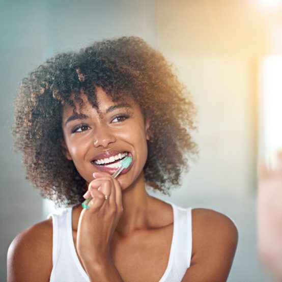 Woman smiling while brushing her teeth