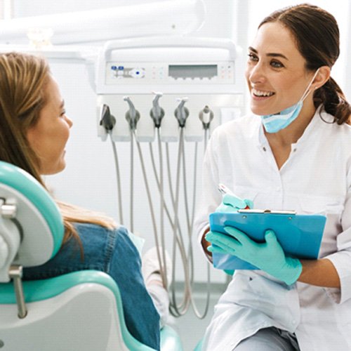 Dentist smiling at patient while taking notes on clipboard